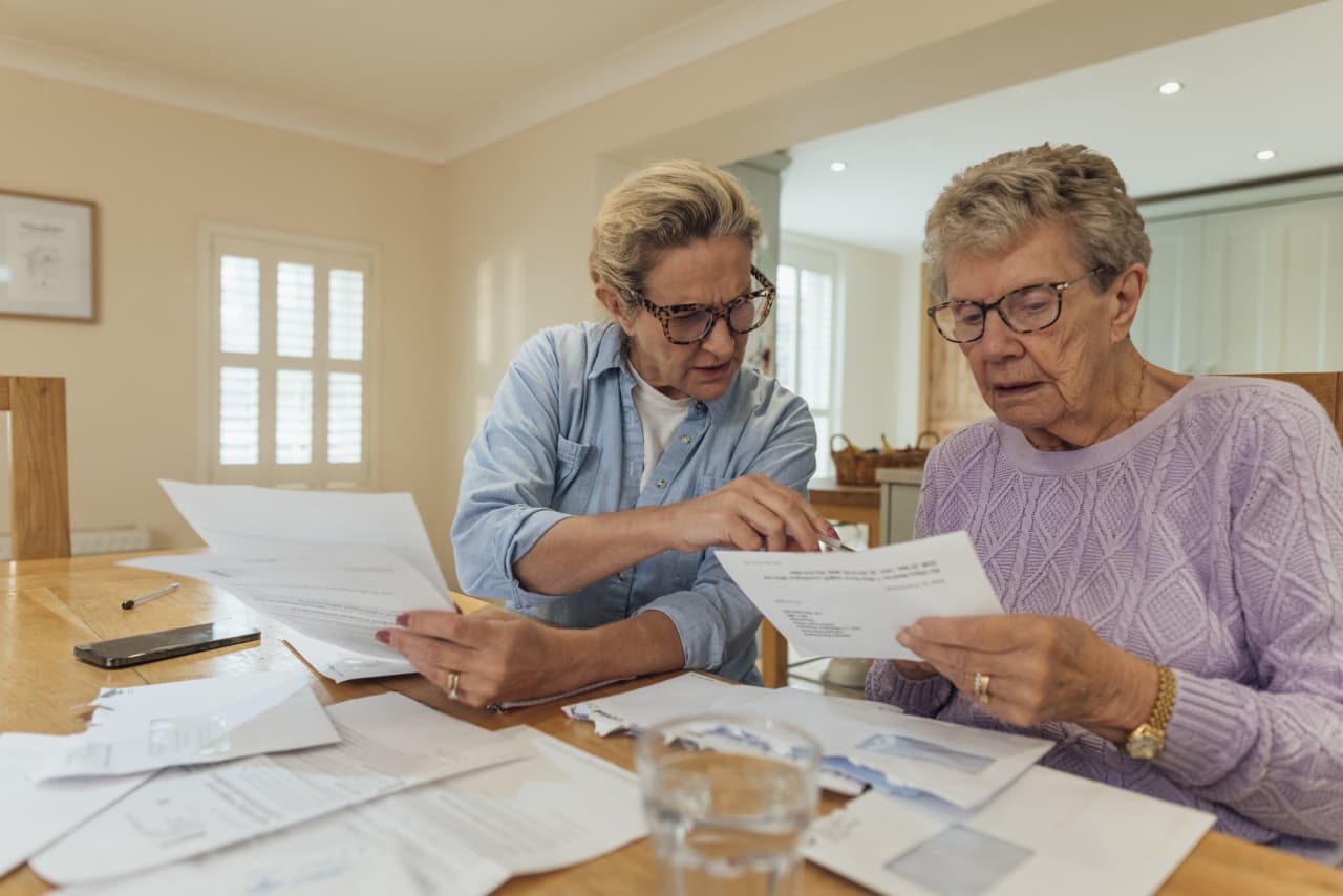 Family caregiver assisting an elderly parent with daily tasks in a New York City apartment, highlighting financial strain.